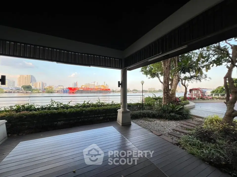 Stunning riverside view from a spacious patio with lush greenery and cityscape backdrop.