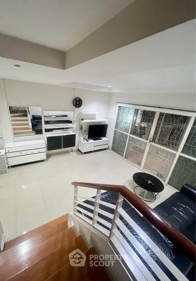 Spacious living room with modern furniture and large windows, perfect for relaxation and entertainment.