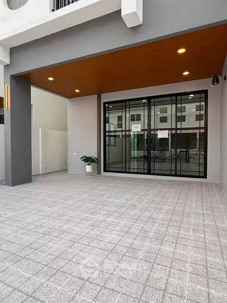 Modern home entrance with sleek design and spacious tiled patio area.