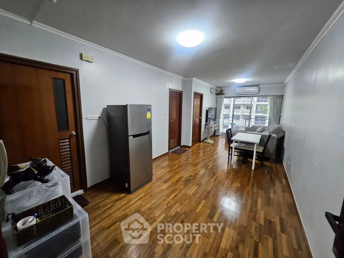 Spacious living room with wooden flooring and modern furniture in a cozy apartment.