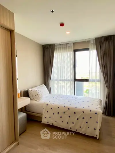 Cozy bedroom with large window and modern decor in a stylish apartment.