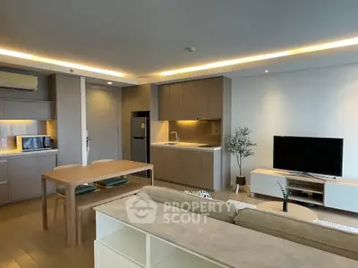 Modern open-plan living room with kitchen, featuring sleek furniture and ambient lighting.