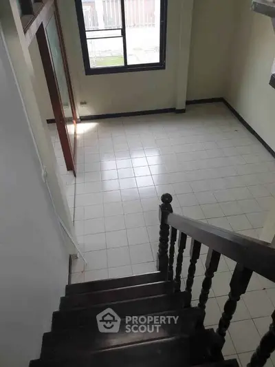 Spacious interior with tiled flooring and wooden staircase, perfect for modern living.
