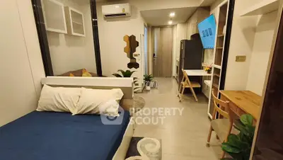 Modern studio apartment with cozy bed, stylish decor, and compact kitchen area, perfect for urban living.