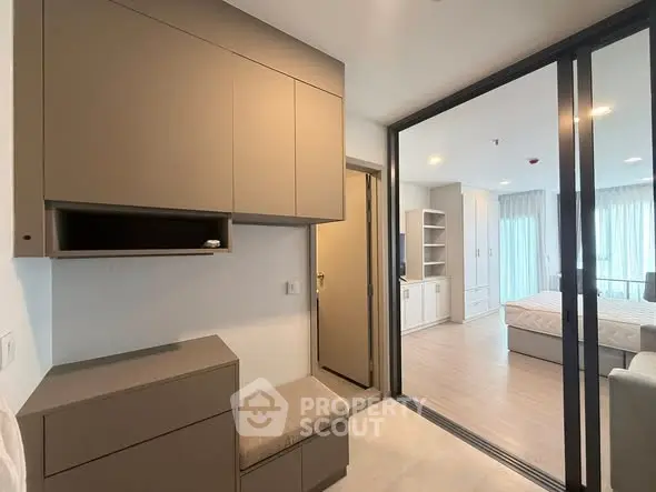 Modern bedroom with sliding glass doors and built-in storage, featuring a cozy seating area.