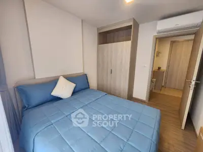 Cozy bedroom with blue bedding and modern wooden wardrobe, perfect for relaxation.