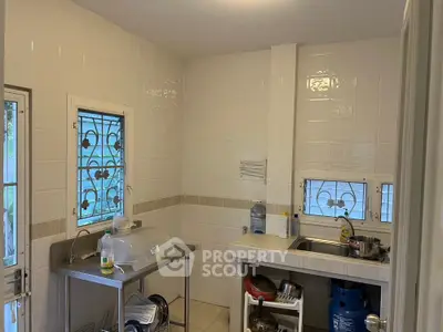 Cozy kitchen with stainless steel counter and tiled walls, featuring a compact layout and natural light.
