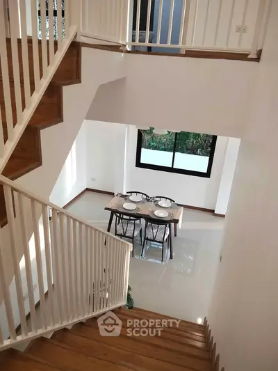 Elegant modern staircase with dining area view in a bright, spacious home interior.