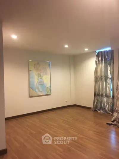 Spacious empty room with wooden flooring and map decor, ideal for customization.