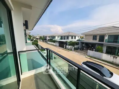 Modern balcony with glass railing overlooking suburban street and houses
