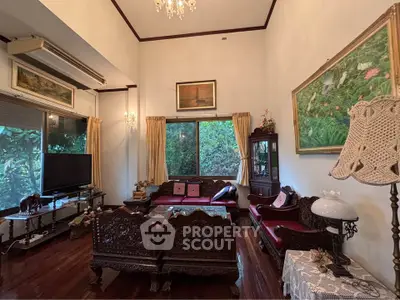 Elegant living room with vintage furniture and lush garden view, perfect for relaxation.