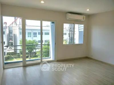 Spacious, well-lit living room with large sliding glass doors leading to a balcony, offering a blend of comfort and natural light.