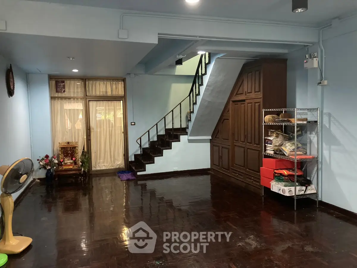 Spacious living room with wooden staircase and storage, ideal for family gatherings.