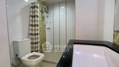 Modern bathroom with sleek design, featuring a shower, toilet, and stylish tile accents.