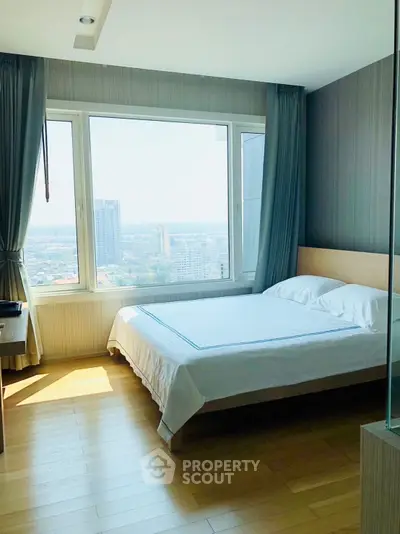 Bright bedroom with large window offering stunning city view in modern apartment.