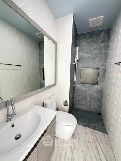Modern bathroom with sleek design, featuring a stylish sink, toilet, and a spacious shower area.
