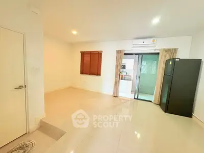 Spacious modern living area with sleek flooring and natural light, featuring a sliding glass door to the kitchen.