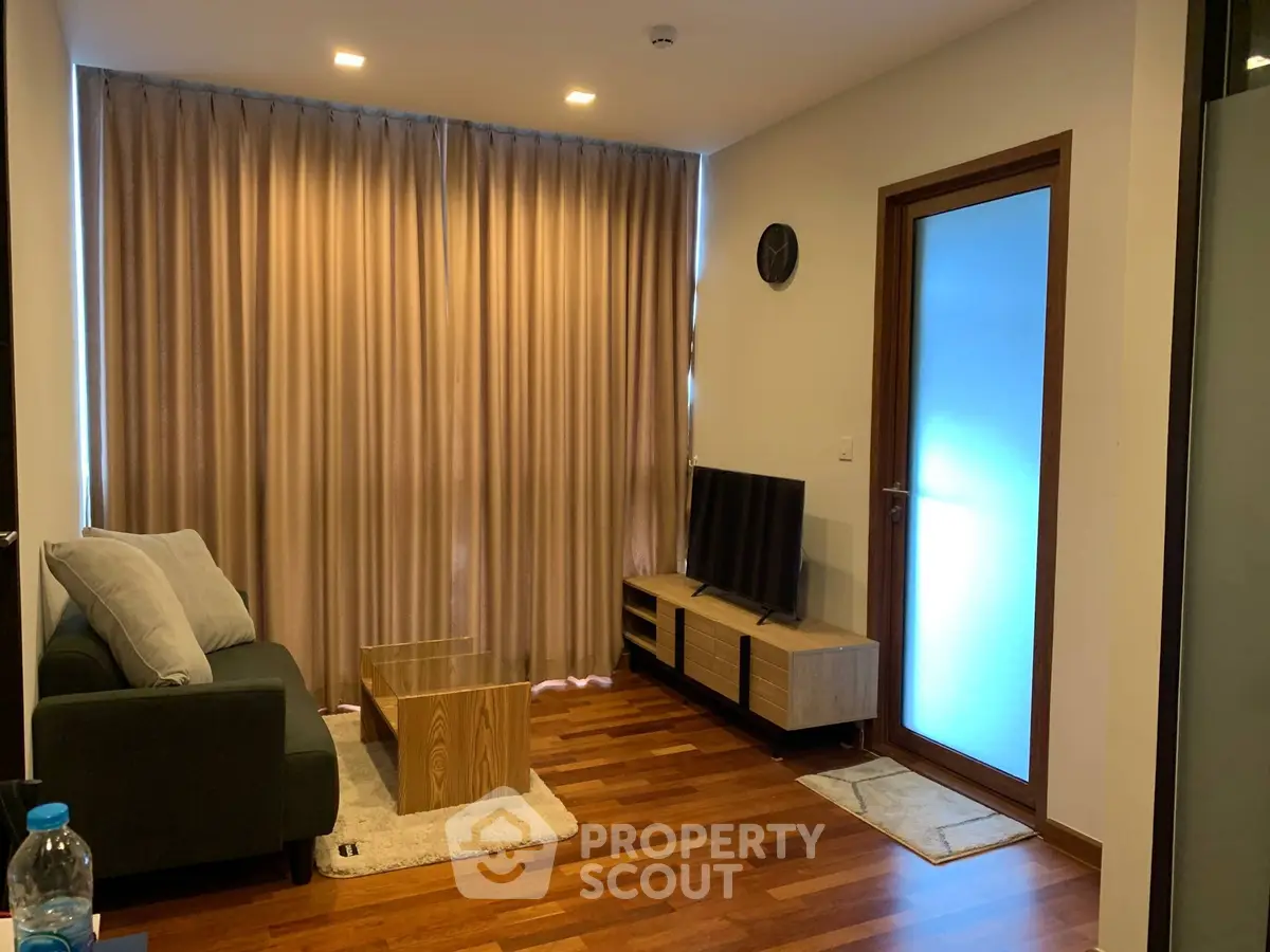 Cozy living room with modern decor and wooden flooring, featuring a comfortable sofa and entertainment unit.
