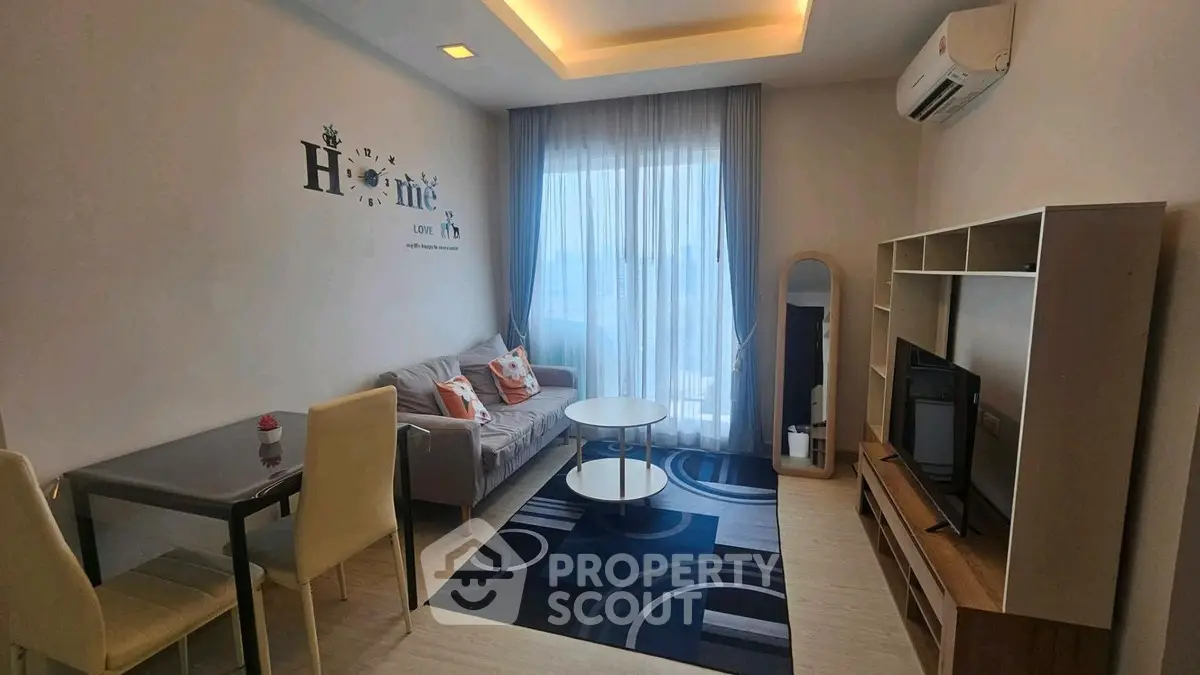 Modern living room with stylish decor, cozy seating, and natural light from large window.