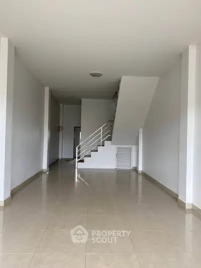 Spacious open-plan interior with staircase, ideal for modern living or office space.