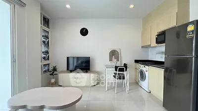 Modern living room with open kitchen, featuring sleek appliances and stylish decor.