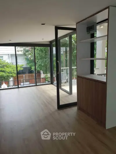 Spacious living room with large windows and balcony access, perfect for natural light lovers.