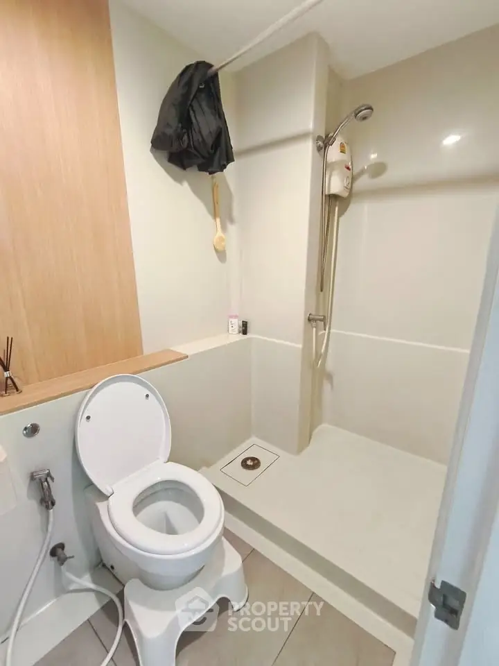 Modern bathroom with shower and toilet in a compact layout, featuring sleek design and neutral tones.