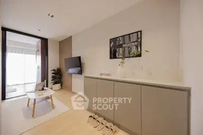 Modern living room with sleek decor and natural light, featuring a wall-mounted TV and stylish furniture.