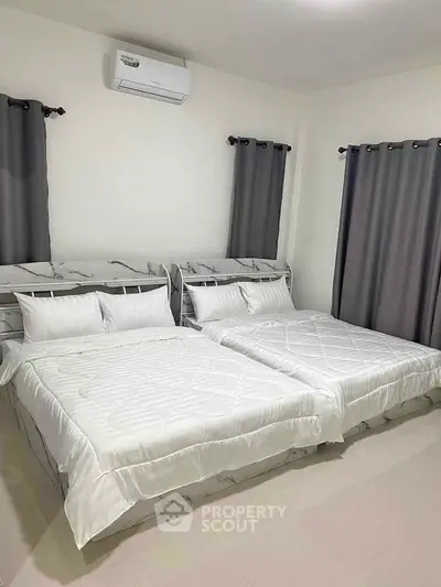 Spacious bedroom with two beds and modern air conditioning unit