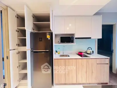 Modern kitchen with sleek cabinetry and stainless steel fridge in a compact layout.