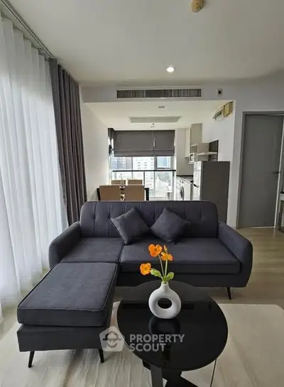 Modern living room with stylish furniture and open kitchen layout in a high-rise apartment.