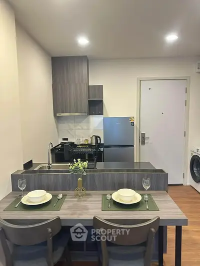Modern kitchen with dining area, featuring sleek cabinetry and stainless steel appliances.