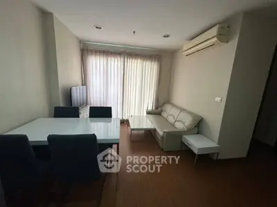 Modern living room with sleek furniture and natural light, featuring a comfortable sofa and dining area.