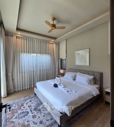 Luxurious bedroom with elegant decor, featuring a king-sized bed, stylish ceiling fan, and large window with curtains.