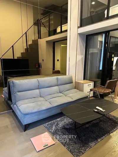 Modern duplex living room with stylish furniture and glass railing staircase