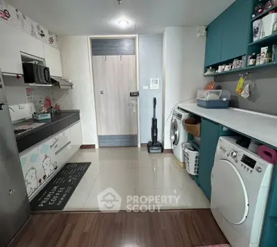 Modern kitchen with teal cabinets and washing machine in cozy apartment