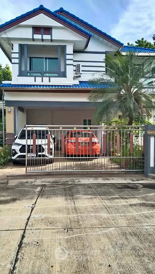 Charming two-story house with blue roof and spacious driveway in a serene neighborhood.