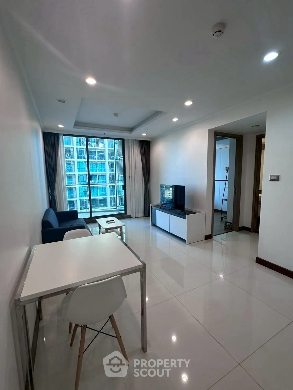 Modern living room with sleek furniture and large windows in a high-rise apartment.