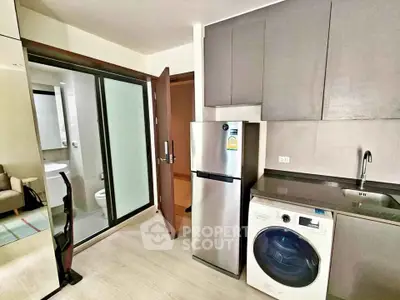 Modern kitchen with sleek appliances and adjacent bathroom in a stylish apartment.