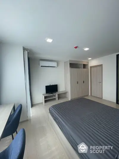 Modern bedroom with sleek design, featuring built-in wardrobe and air conditioning.