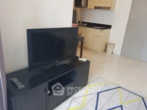Modern living room with sleek TV stand and compact kitchen area in open layout apartment.