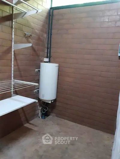 Spacious utility room with brick walls and water heater, ideal for storage or laundry setup.