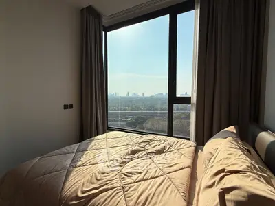 Cozy bedroom with large window offering stunning cityscape views, perfect for urban living.