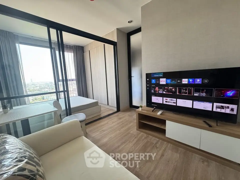 Modern living room with open layout and city view, featuring a cozy sofa and large TV.