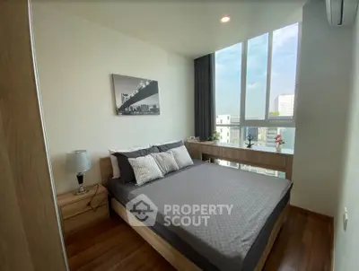 Modern bedroom with large windows and city view, featuring stylish decor and cozy ambiance.