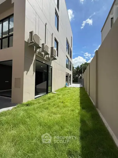 Modern building exterior with lush green lawn and clear blue sky