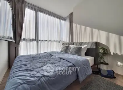 Modern bedroom with large windows and stylish decor, featuring a cozy bed and elegant curtains.