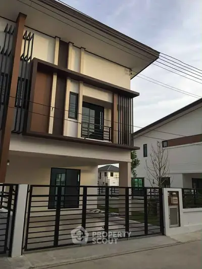 Modern two-story house with sleek architectural design and gated entrance in a suburban neighborhood.