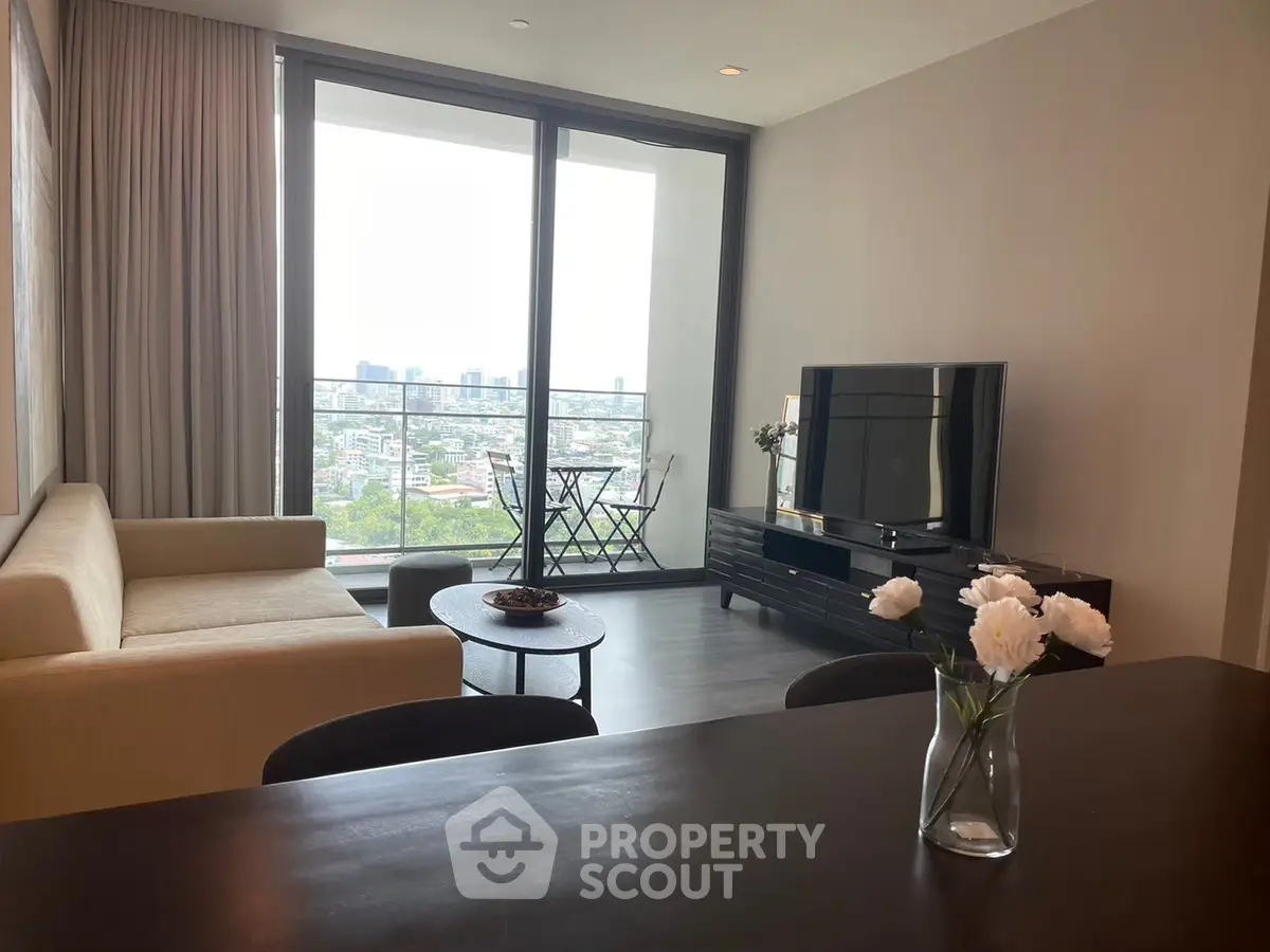 Modern living room with city view, stylish furniture, and balcony access in a high-rise apartment.