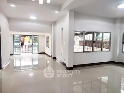 Spacious open-plan living room with large windows and glossy tiled floors